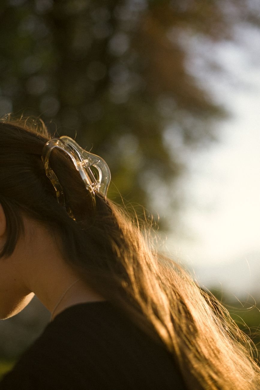 A woman's hair caught in warm sunlight, styled with a beautiful claw clip