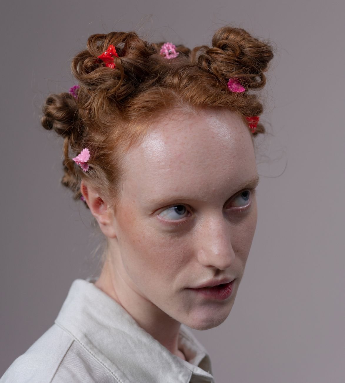 Close-up of a woman with ginger hair styled in buns, wearing colorful decorative hair clips