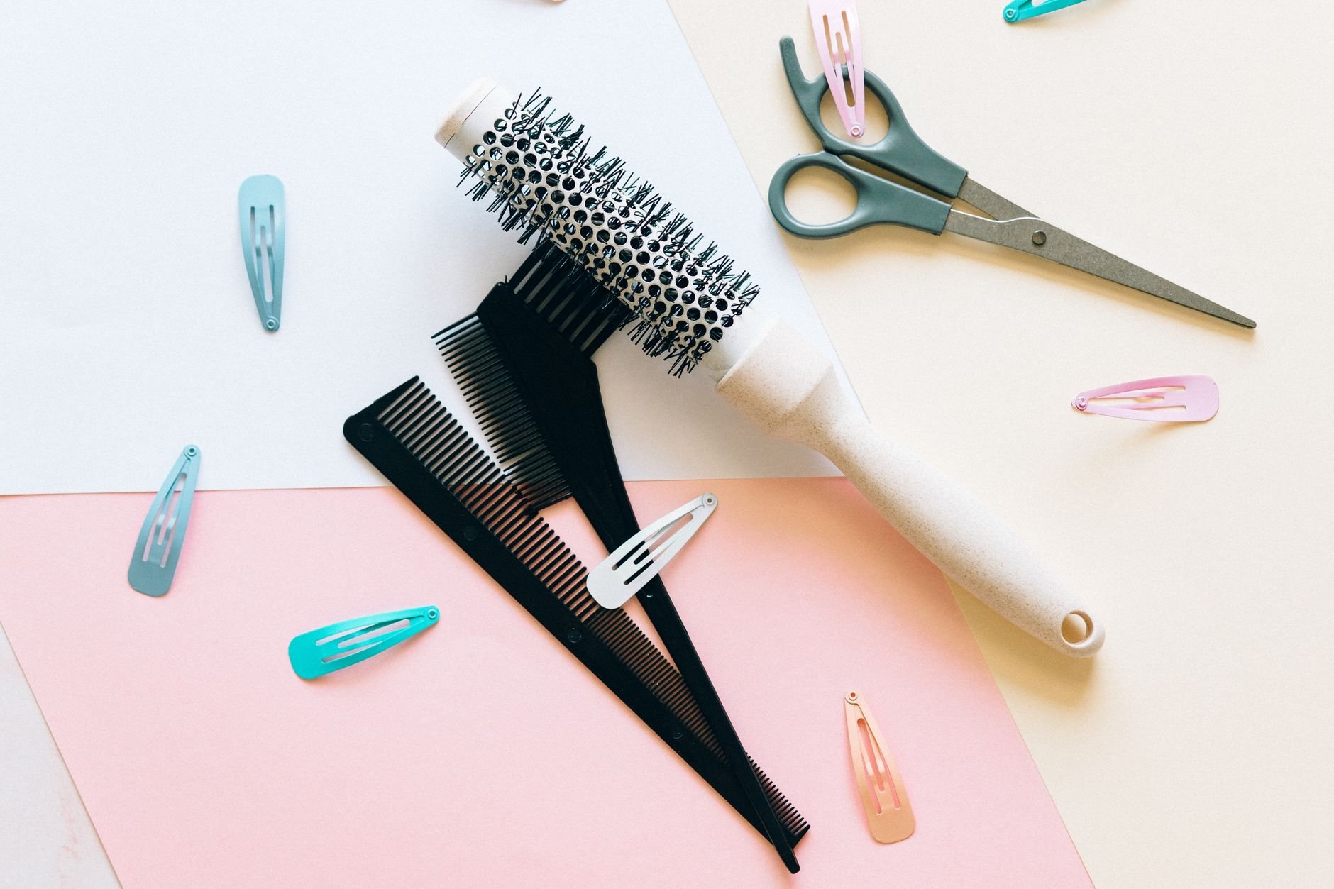 A flat lay of hair clips and styling tools arranged on a pastel surface